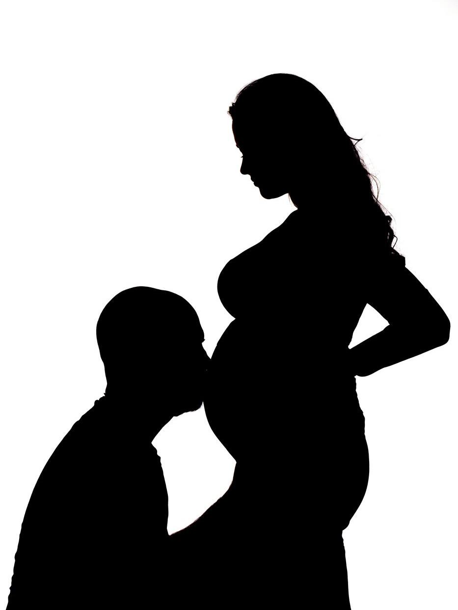 Ein Silhouetten Foto mit den werdenden Eltern. Julia küßt den Bauch seiner Frau.